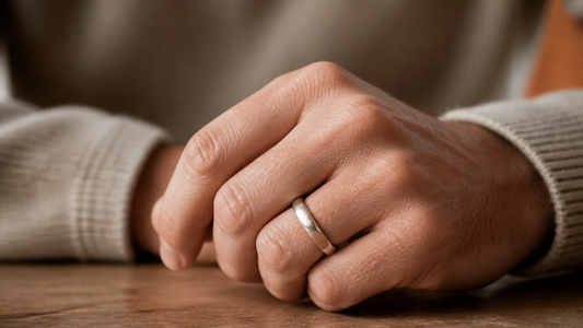 A man's hand wearing a modern, elegant engagement band, symbolizing commitment and love.
