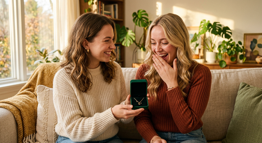 Two best friends sharing a jewelry gift moment on a cozy couch with warm golden light